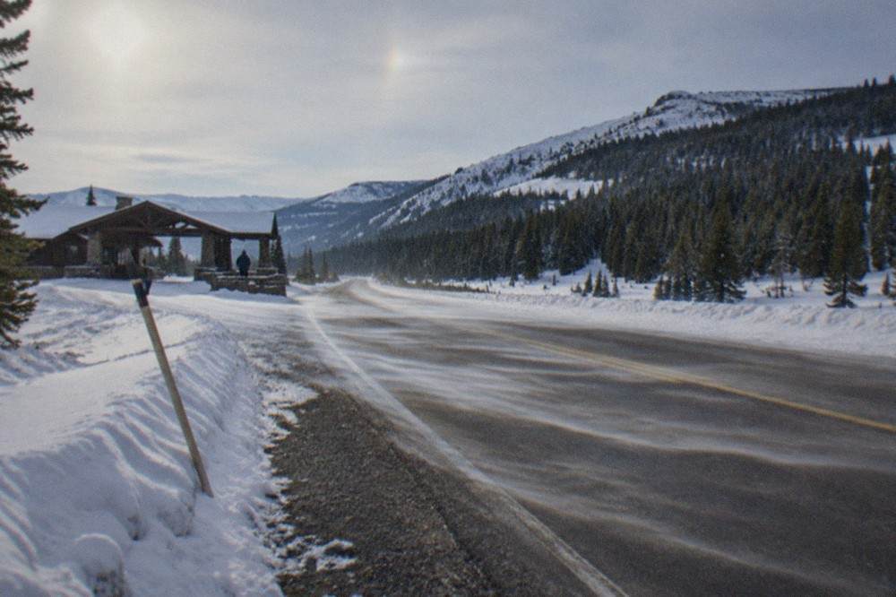 A plowed winter road through snow-covered forest and mountains in Yellowstone's northern range