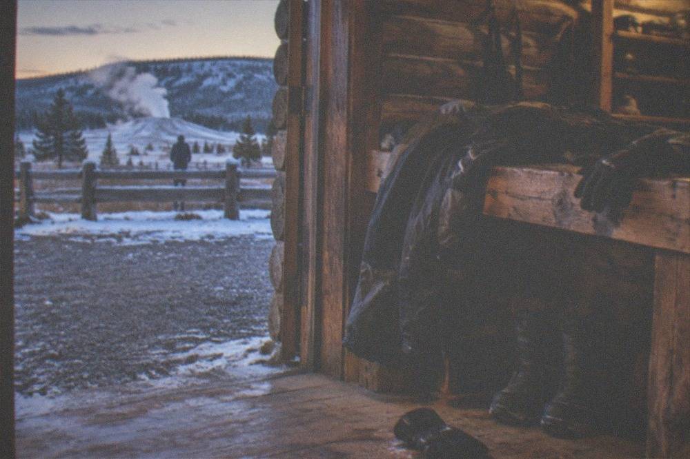 Insulated snowmobile suit jacket and gloves laid out on a wooden bench before a winter ride