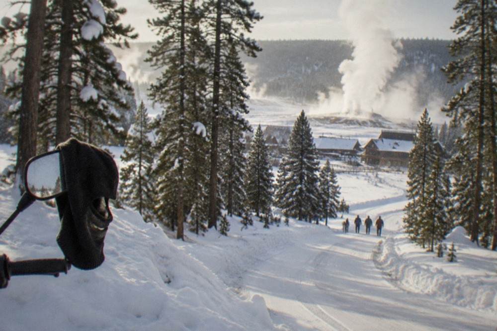 Groomed snow road winding between snowy pine trees in Yellowstone winter