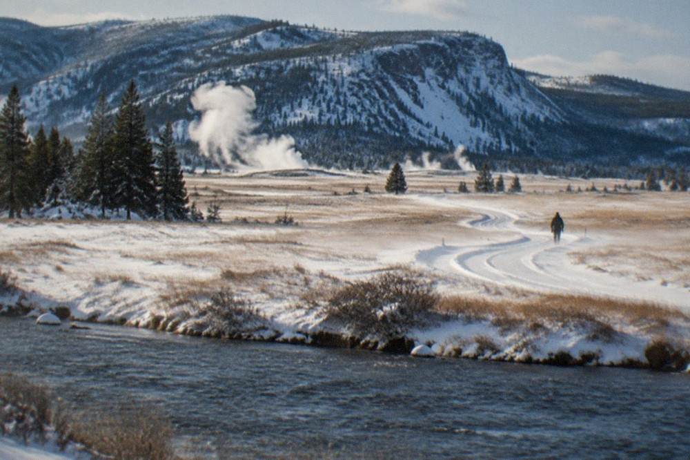 Wide snowy valley with a winding road and distant mountain range