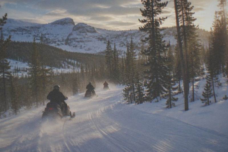 Guided snowmobile group riding a groomed trail through Bridger-Teton National Forest