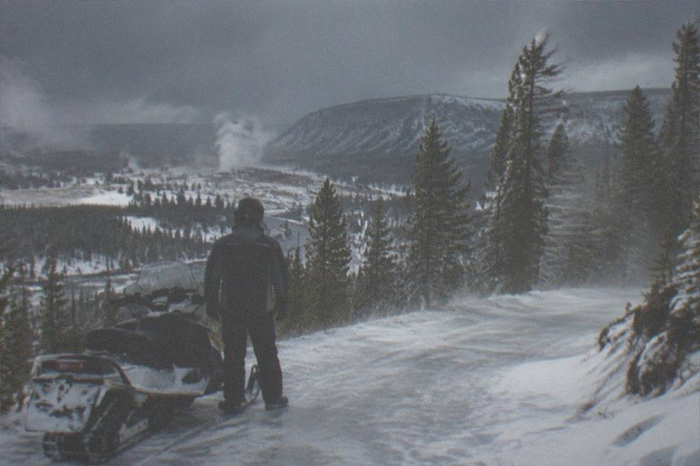 Snowmobile rider in insulated suit and helmet stopped on a snowy forest trail