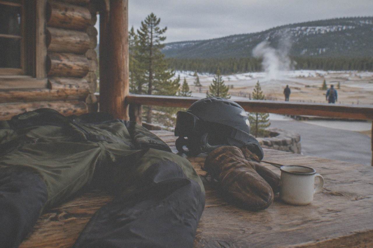 Insulated snowmobile suits, helmets and boots arranged on a wooden bench inside a warm lodge before a winter tour