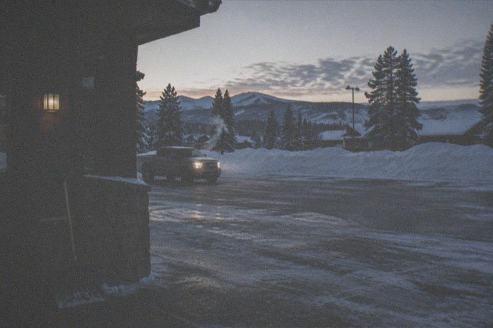 A plowed hotel parking lot with snowbanks and a truck warming up at dawn