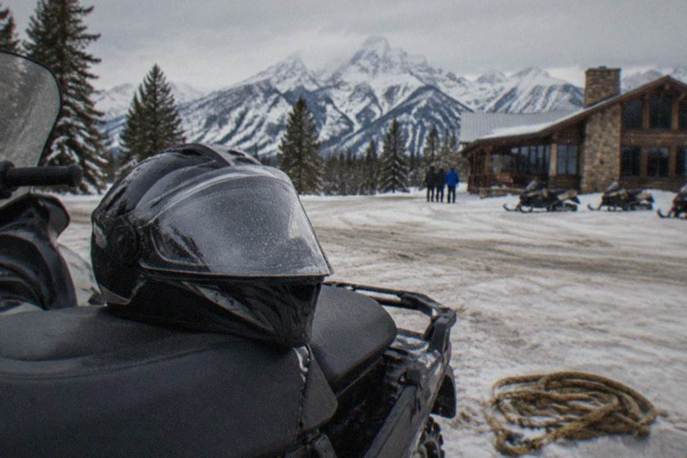 A helmet resting on the seat of a snowmobile at a winter staging area