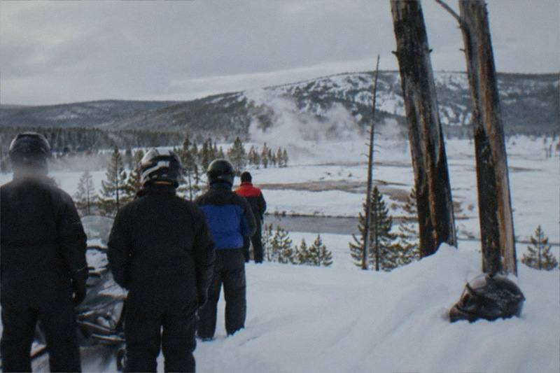Snowmobile tour group at Old Faithful geyser on a full-day trip from Jackson Hole